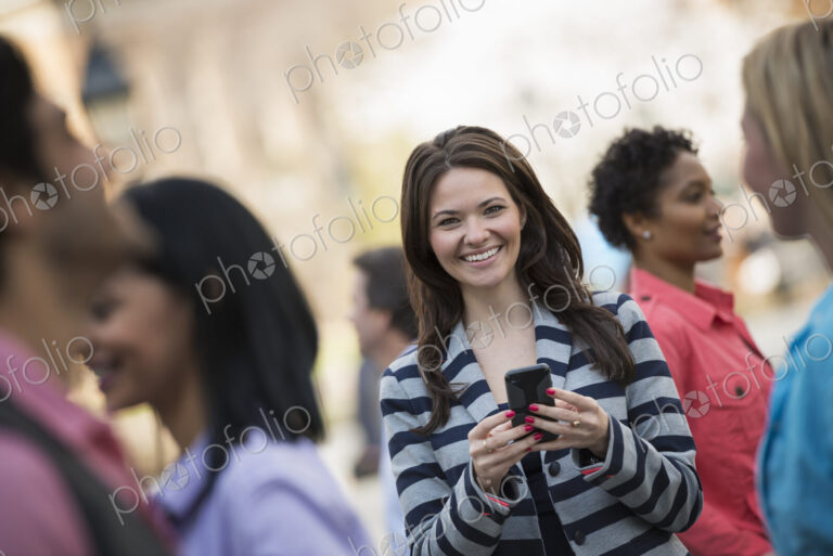 People outdoors in the city in spring time. New York City park. A young woman holding…