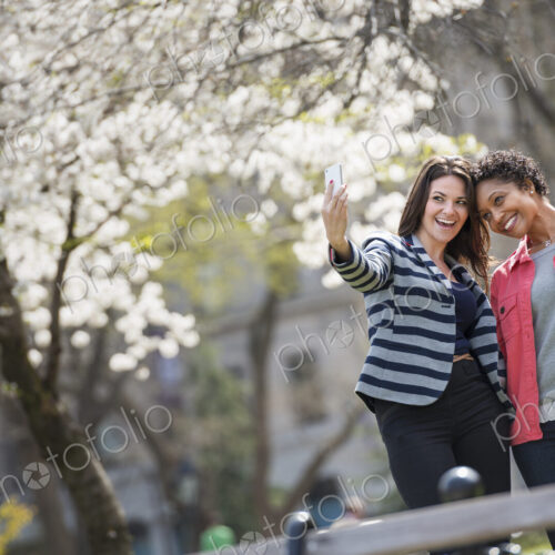 People outdoors in the city in spring time. New York City park. A young woman holding… People outdoors in the city in spring time. New York City park. A young woman holding…