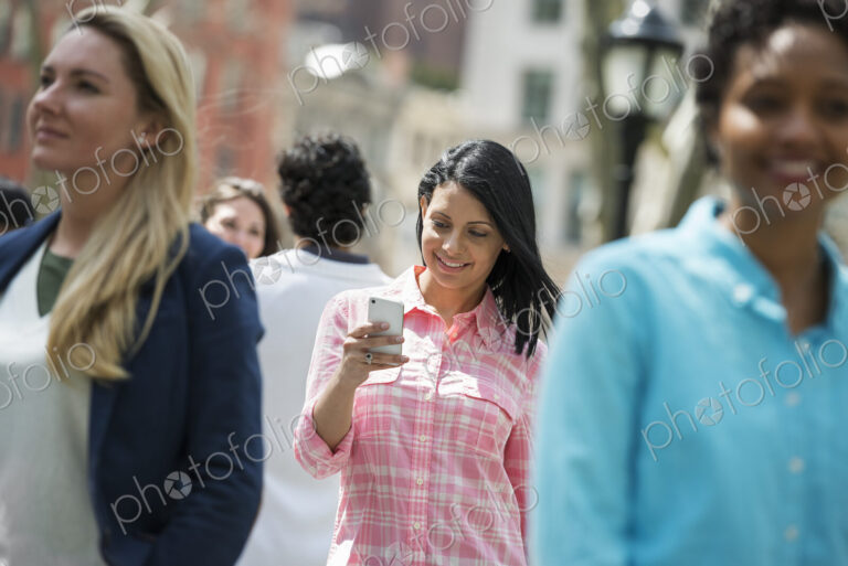 People outdoors in the city in spring time. New York City park. Three women, one…