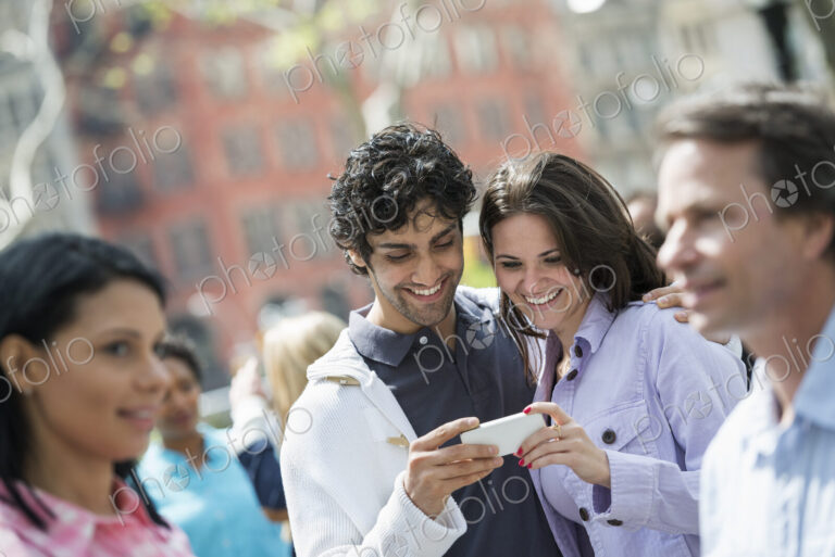 People outdoors in the city in spring time. New York City. A group of men and women, a…