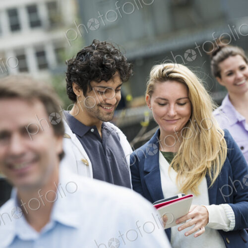 People outdoors in the city in spring time. New York City. A group of men and women, a… People outdoors in the city in spring time. New York City. A group of men and women, a…