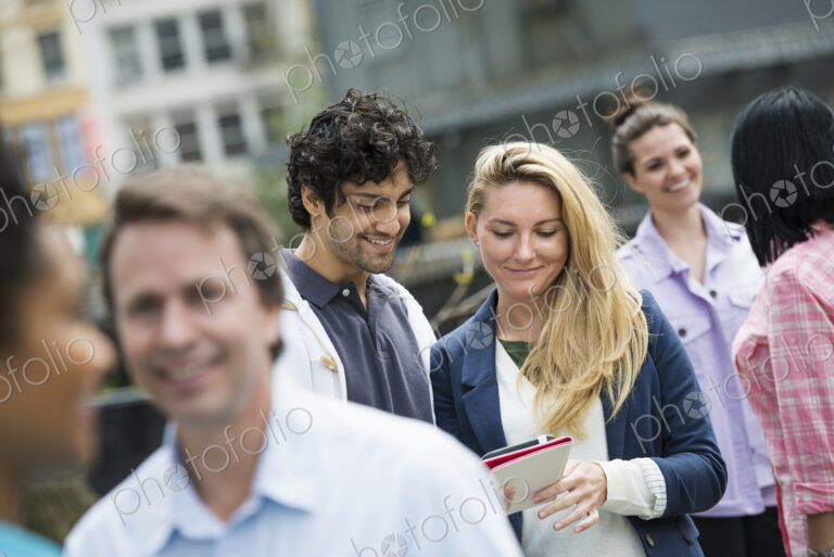 People outdoors in the city in spring time. New York City. A group of men and women, a…