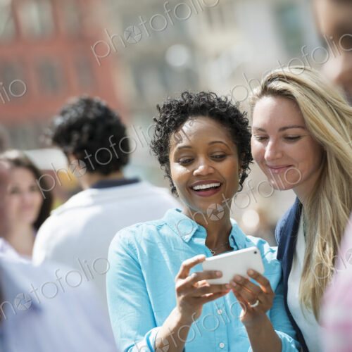 People outdoors in the city in spring time. New York City. A group of men and women,…