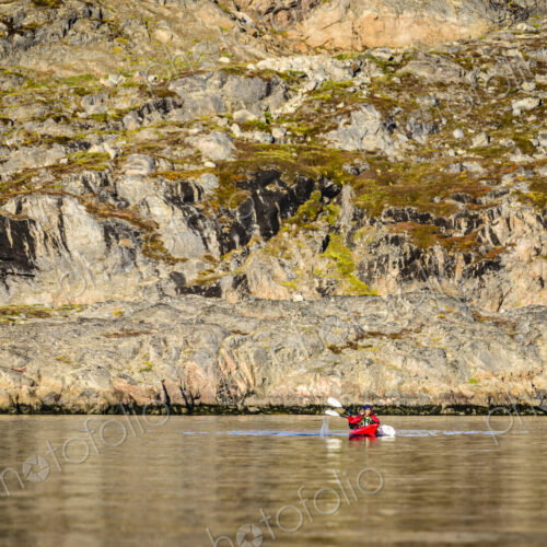People paddling canoe near rock formations in remote river