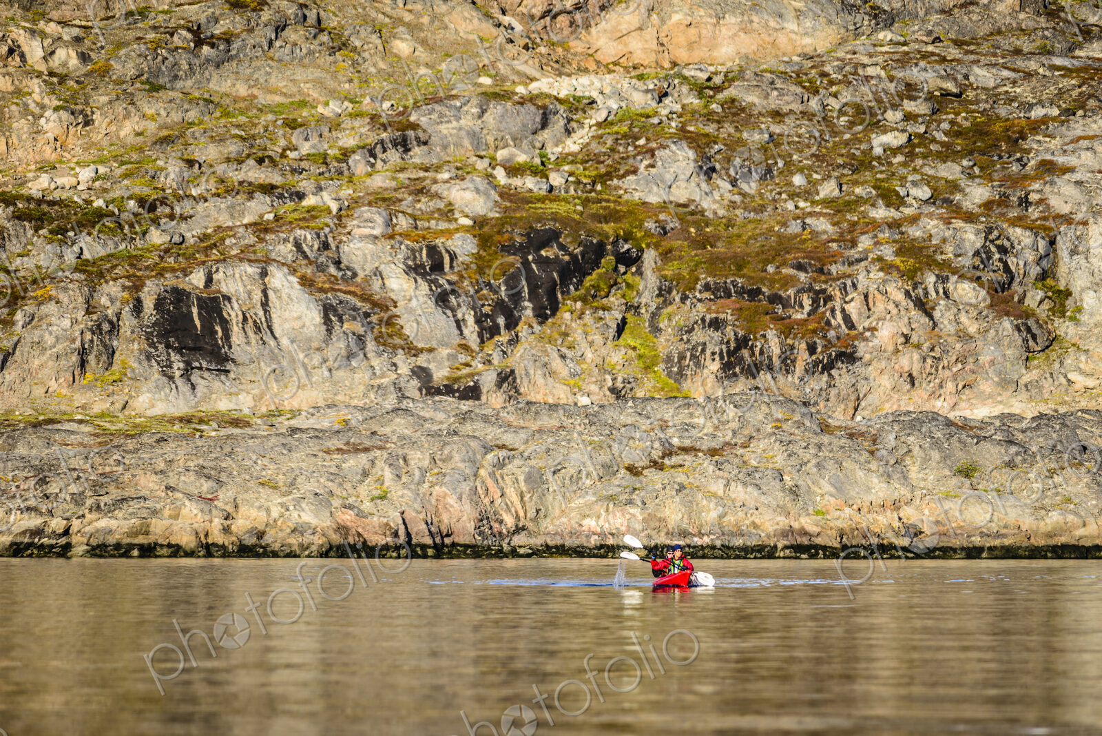 People paddling canoe near rock formations in remote river
