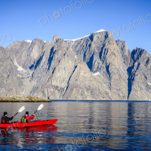 People paddling canoe near rock formations in remote river People paddling canoe near rock formations in remote river