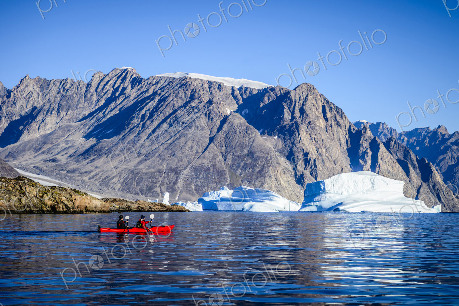 People paddling canoe near rock formations in remote river