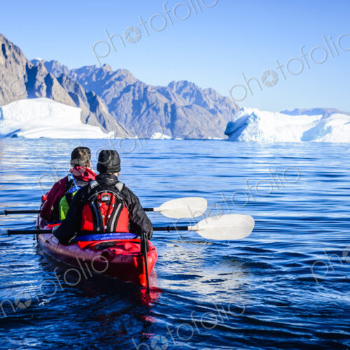 People paddling canoe towards glaciers in remote river People paddling canoe towards glaciers in remote river