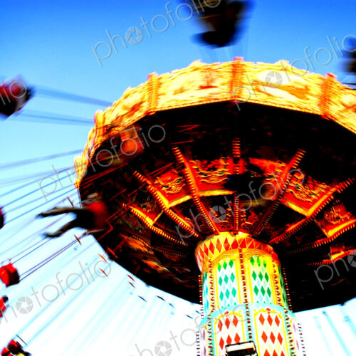 People riding on a chair swing ride or swing carousel seen from below. People riding on a chair swing ride or swing carousel seen from below.