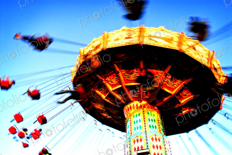 People riding on a chair swing ride or swing carousel seen from below.