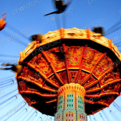People riding on a chair swing ride or swing carousel seen from below. People riding on a chair swing ride or swing carousel seen from below.