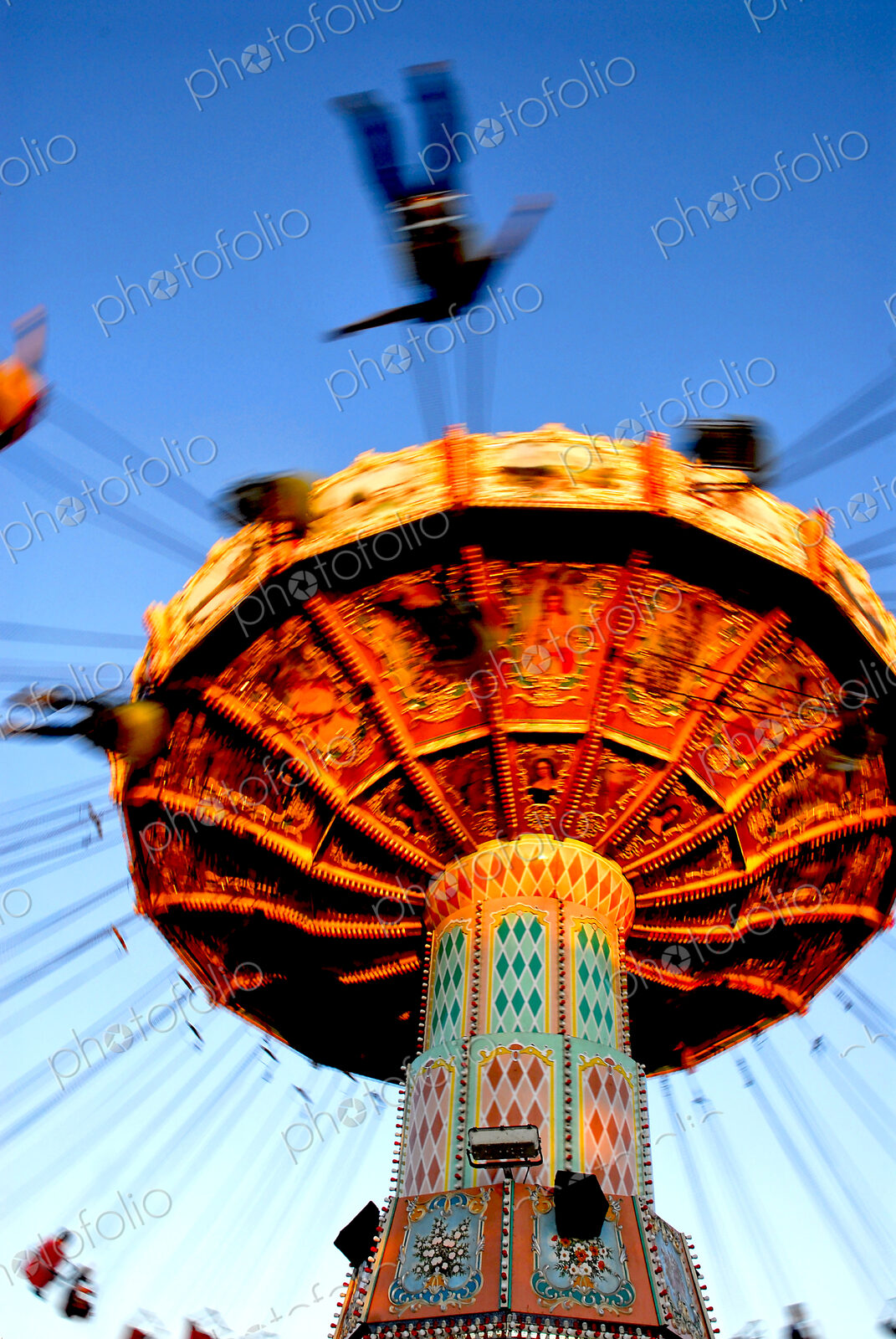 People riding on a chair swing ride or swing carousel seen from below.