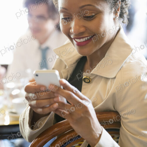 People sitting in a cafe or bar around a table checking their smart phones. People sitting in a cafe or bar around a table checking their smart phones.