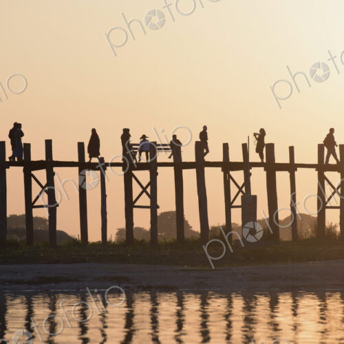 People walking on elevated wooden walkway at sunset People walking on elevated wooden walkway at sunset