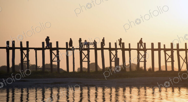 People walking on elevated wooden walkway at sunset
