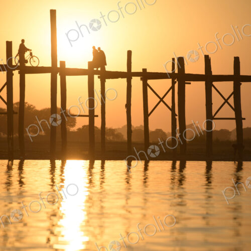 People walking on elevated wooden walkway at sunset People walking on elevated wooden walkway at sunset