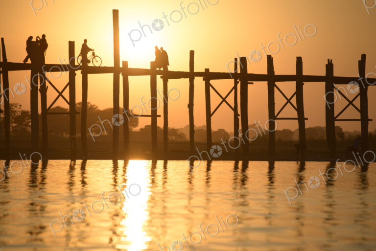 People walking on elevated wooden walkway at sunset