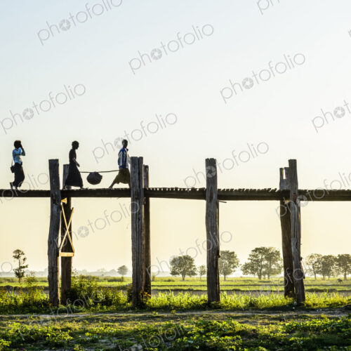 People walking on elevated wooden walkway in rural landscape