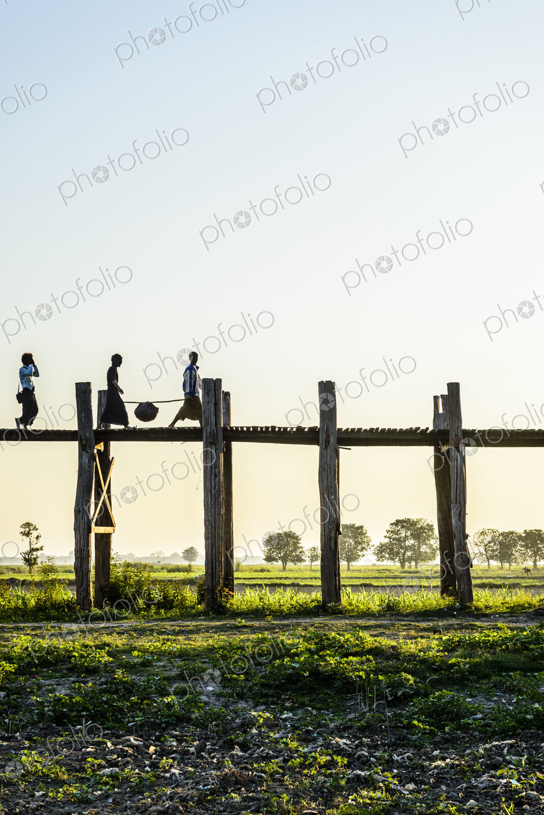 People walking on elevated wooden walkway in rural landscape