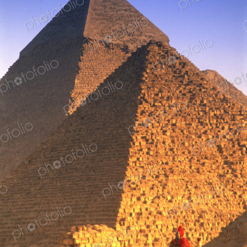 Person on camel in front of Egyptian pyramids.