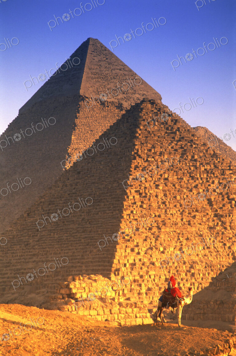 Person on camel in front of Egyptian pyramids.