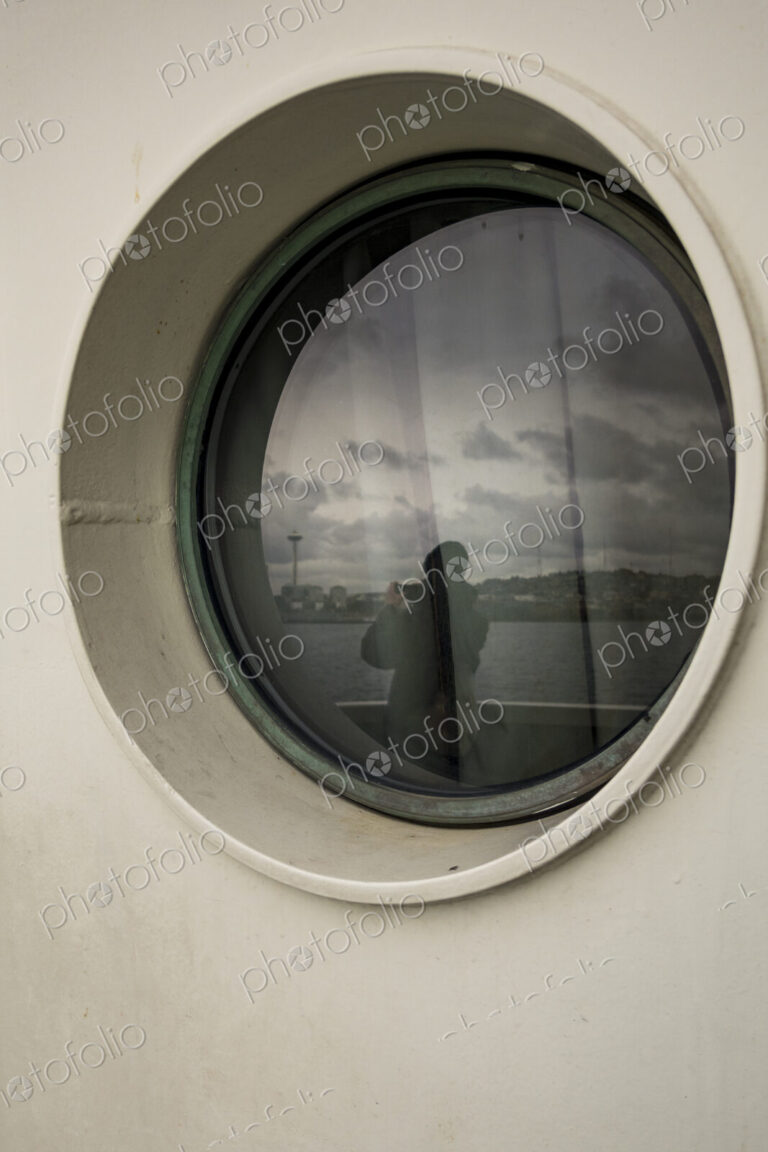 Person taking photo of Seattle's Space Needle, view through a Porthole on a Seattle ferry.