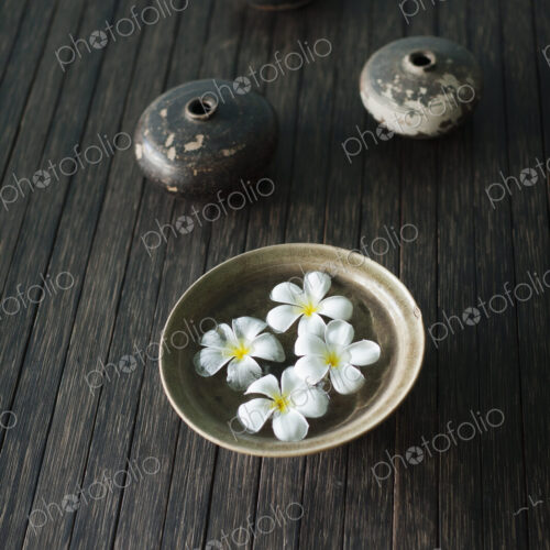 Petals of the orchid flower in a bowl of water. Oil lamps.