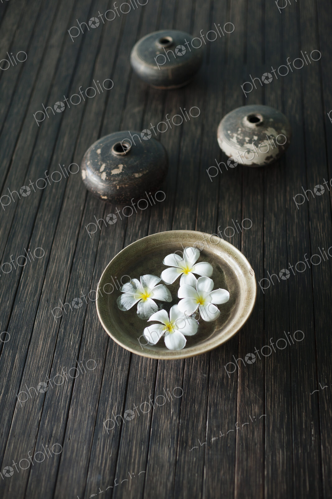 Petals of the orchid flower in a bowl of water. Oil lamps.