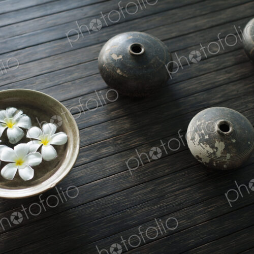 Petals of the orchid flower in a bowl of water. Oil lamps.