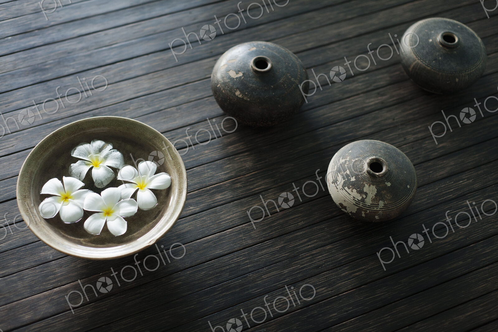 Petals of the orchid flower in a bowl of water. Oil lamps.