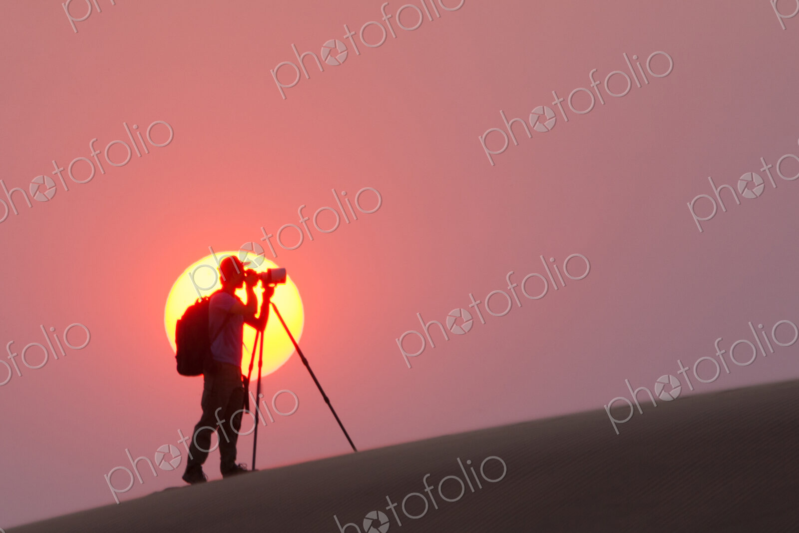 Photographer silhouetted in the setting sun in the Namib Desert, Namibia