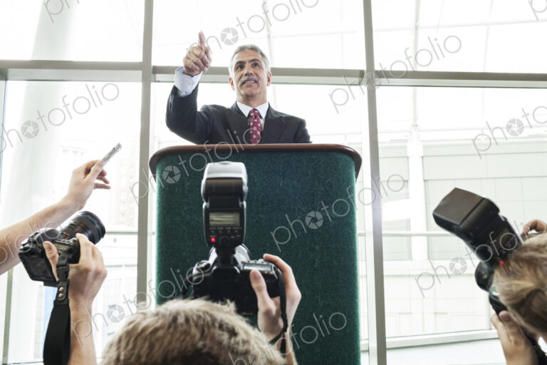 Photographers taking photographs at a political gathering and speech.