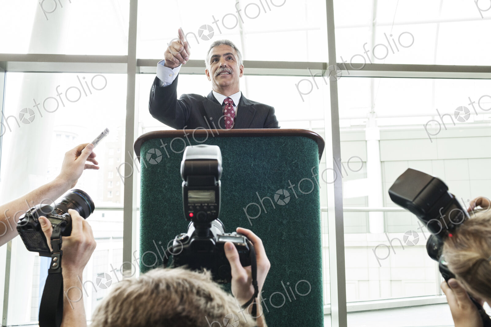 Photographers taking photographs at a political gathering and speech.