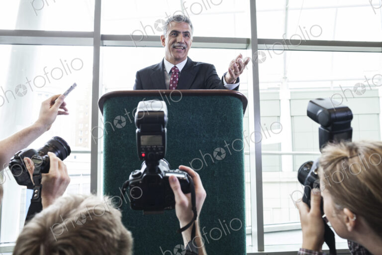 Photographers taking photographs at a political gathering and speech.