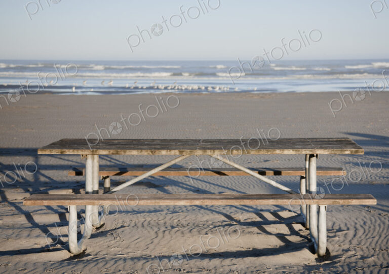 Picnic table on sandy beach.