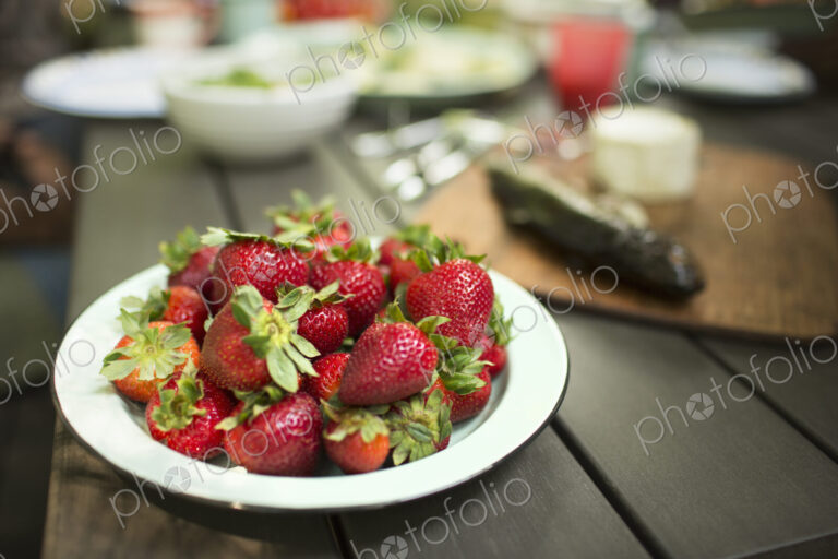 Picnic table with a meal laid out. A place of fresh strawberries.