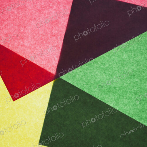 Pieces of colorful, recycled construction paper, overlapping and laid out at random.