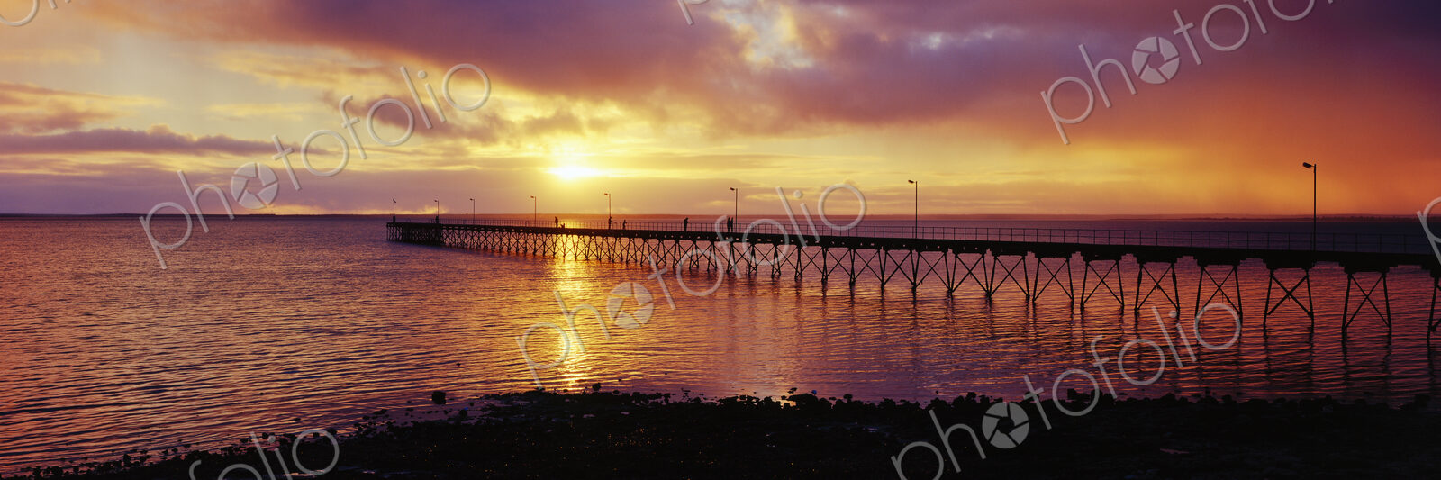 Pier in the sea with sunset on the horizon of the ocean.