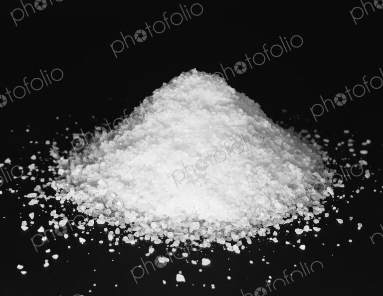 Pile of coarse sea salt grains on a black background.