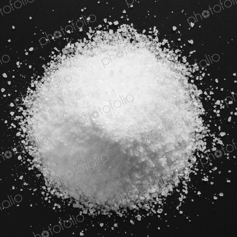 Pile of coarse sea salt grains on a black background.