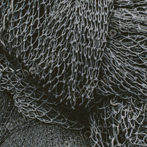 Pile of commercial fishing nets and gill nets on a fishing quay.