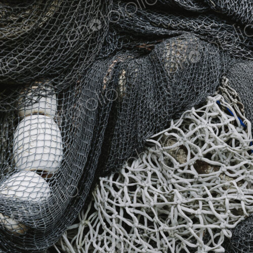 Pile of commercial fishing nets and gill nets on a fishing quay.