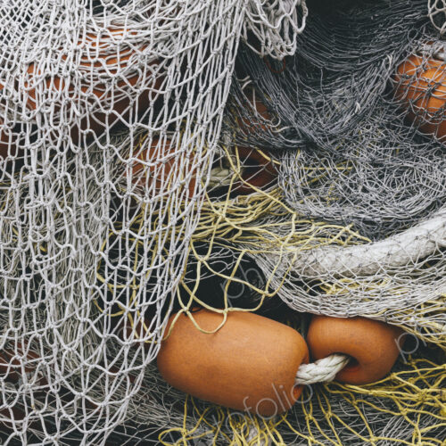 Pile of commercial fishing nets and gill nets on a fishing quay.