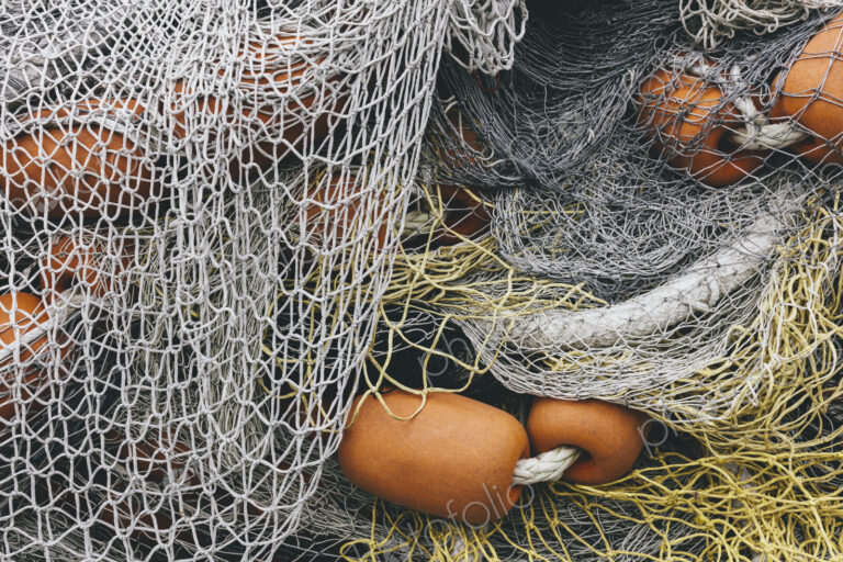Pile of commercial fishing nets and gill nets on a fishing quay.