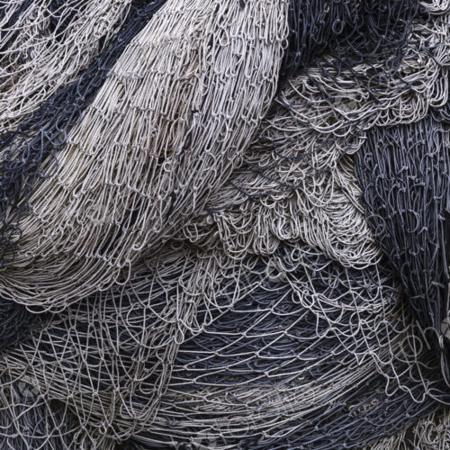 Pile of commercial fishing nets and gill nets on a fishing quay.