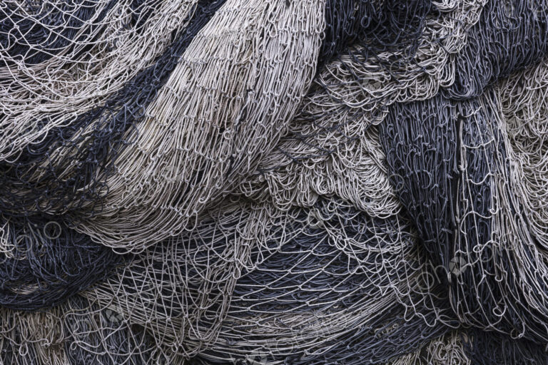 Pile of commercial fishing nets and gill nets on a fishing quay.