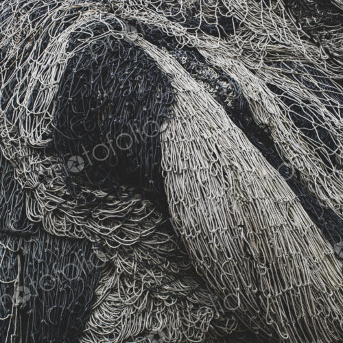 Pile of commercial fishing nets and gill nets on a fishing quay.