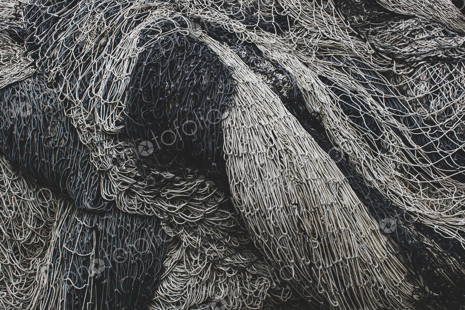 Pile of commercial fishing nets and gill nets on a fishing quay.