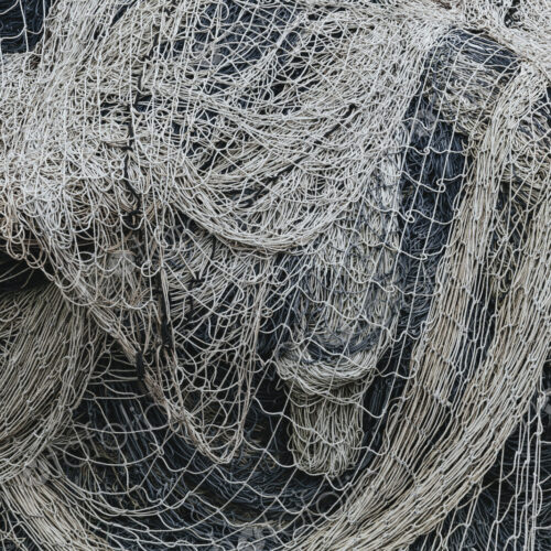 Pile of commercial fishing nets and gill nets on a fishing quay.