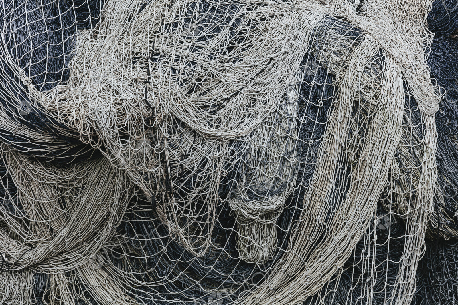 Pile of commercial fishing nets and gill nets on a fishing quay.